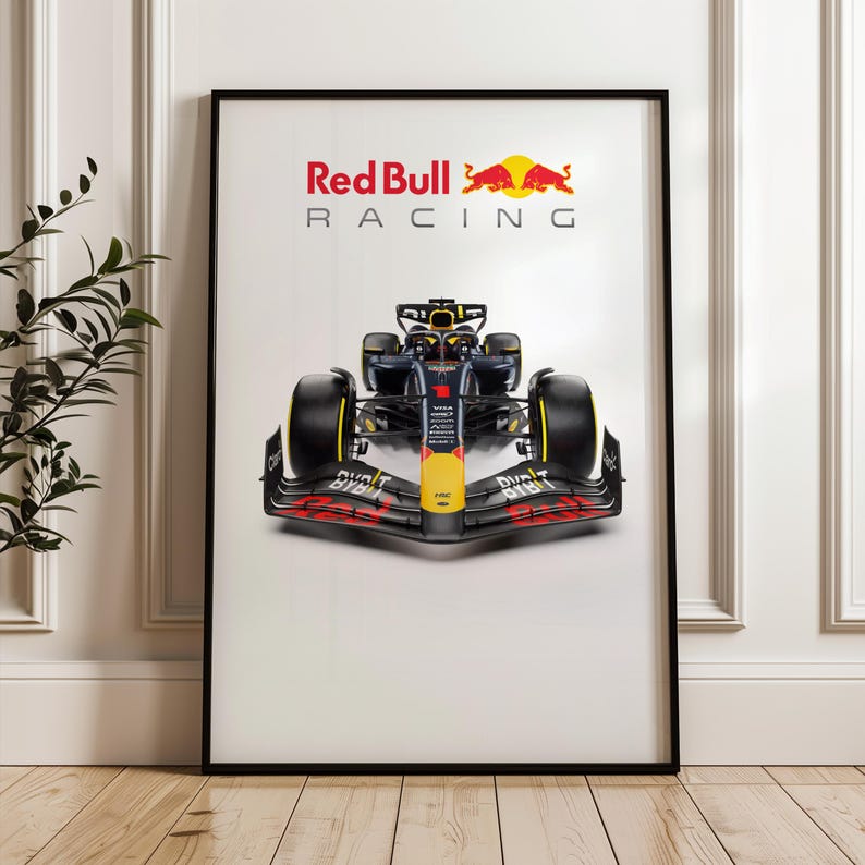 May include: Framed poster featuring a Red Bull Racing Formula 1 car. The car is predominantly navy blue, yellow, and red, with large black tires. The Red Bull Racing logo is displayed at the top, above the car.
