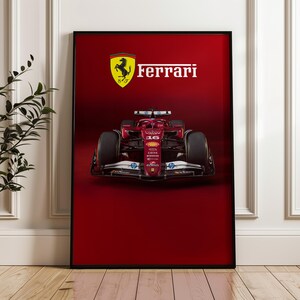 May include: Framed poster featuring a red Ferrari Formula 1 race car. The Ferrari logo, a black prancing horse on a yellow shield, is above the car, with the name "Ferrari" in white. The background is a solid red.