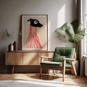 Puede incluir: Una ilustraci&oacute;n en blanco y negro de un perro con un su&eacute;ter a rayas rojas y blancas. La ilustraci&oacute;n est&aacute; enmarcada y colgada en una pared sobre un gabinete de madera y un sill&oacute;n verde.