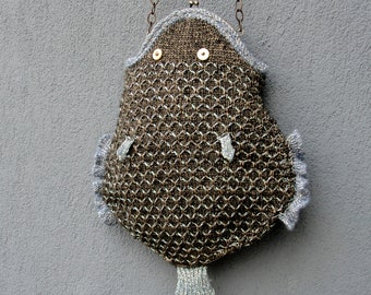 Può includere: Una borsa di maglia marrone a forma di pesce con una tracolla a catena. La borsa ha un bordo grigio e due occhi a bottone.