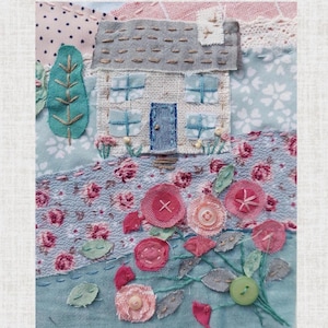 Close up of cottage and roses. Stitched with complementary thread. The roses are layered circles of fabric and mesh in pinks with green stitched stem and fabric leaves. Buttons are on the flowers. Flowers stitched around the cottage.