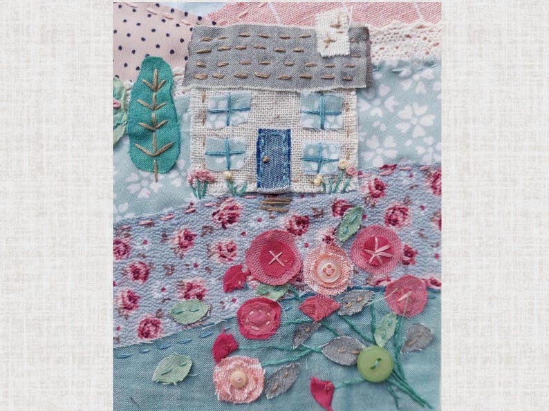 Close up of cottage and roses. Stitched with complementary thread. The roses are layered circles of fabric and mesh in pinks with green stitched stem and fabric leaves. Buttons are on the flowers. Flowers stitched around the cottage.