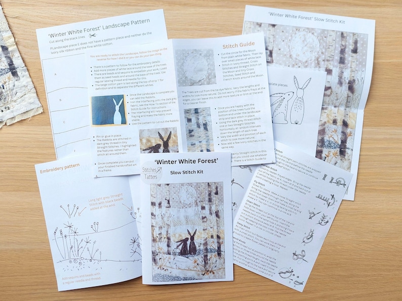May include: A collection of printed instruction sheets for a "Winter White Forest" slow stitch kit. The sheets include patterns, stitch guides, and illustrations of rabbits and forest scenes. The color palette is primarily black, white, and gray.