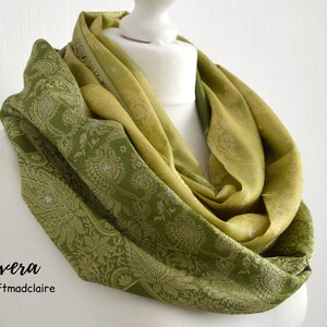 May include: A green and yellow ombre infinity scarf with a paisley pattern. The scarf is made of a soft, silky fabric and is perfect for adding a touch of elegance to any outfit.