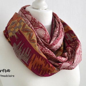 May include: A burgundy, pink, and orange patterned infinity scarf with a geometric design. The scarf is made of a soft, lightweight fabric and is perfect for adding a touch of color to any outfit.