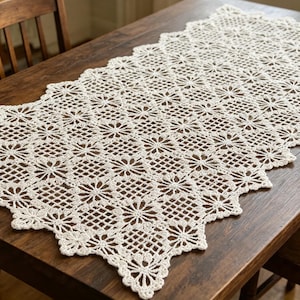 May include: A rectangular off-white crochet table runner featuring a repeating pattern of floral motifs and openwork grid squares. The edges of the runner have a scalloped design with pointed corners, showcasing intricate needlework throughout.
