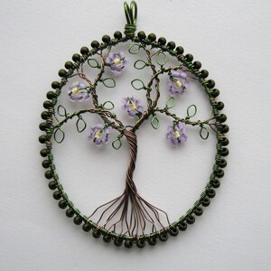 Photo of a beaded oval pendant, featuring a wire tree with leaves and lilac flowers