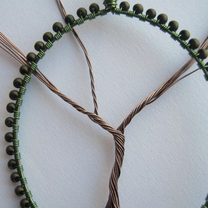 Close-up of a beaded oval frame and a wire tree in progress