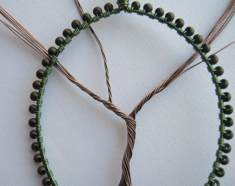 Close-up of a beaded oval frame and a wire tree in progress