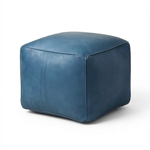 May include: A square, blue leather ottoman. The ottoman is a solid color and has a smooth, slightly textured surface. The edges are neatly stitched, and the overall design is simple and modern. It is a versatile piece of furniture.