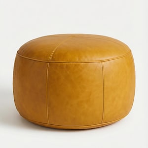 May include: A round, mustard-colored ottoman with a stitched design. The leather-like material has a smooth texture and a warm, inviting hue. The ottoman is a versatile piece of furniture, suitable for various interior styles.