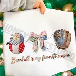 Puede incluir: Tela blanca con bordados con temática de béisbol. Presenta una gorra de béisbol, una pelota de béisbol, un lazo y un guante de béisbol. El texto "Baseball is my favorite season" también está bordado.