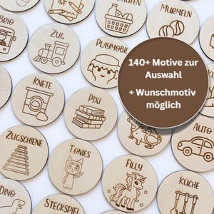 Könnte beinhalten: Runde Holz-Token mit eingravierten Illustrationen und Text. Die Token zeigen verschiedene Designs, darunter eine Lokomotive, ein Auto, ein Einhorn und den Text "140+ Motive zur Auswahl + Wunschmotiv möglich". Die Token sind hellbraun.
