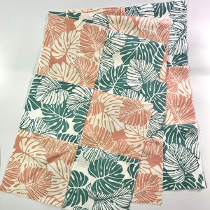 May include: Multiple fabric squares featuring a repeating pattern of large tropical leaves in coral, green, and white. The leaves are stylized and arranged in a grid-like design. The fabric appears to be cotton or a similar material.