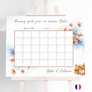 Peut inclure: Un panneau blanc sur un chevalet avec une grille de calendrier pour un jeu de baby shower. Le panneau présente des accents d'aquarelle de feuilles et de citrouilles bleues et oranges. Le texte en cursive se lit "Devinez quel jour va arriver Bébé ?" et "Bébé d'Automne".