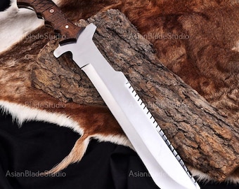 May include: A large, silver blade knife with a wooden handle. The blade has a serrated edge and a distinctive shape. The handle is dark brown with a textured grip. The knife rests on a piece of wood and fur.