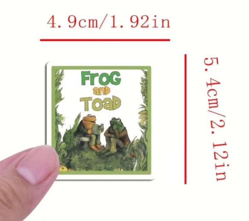以下が含まれることがあります： 「Frog and Toad」の表紙が描かれた正方形のステッカー。ステッカーの幅は4.9cm、高さは5.4cmです。緑と茶色の背景に、2匹の人格化されたカエルが描かれており、タイトルテキストは緑色です。