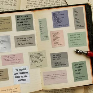 May include: A vintage book open to a page with several quote cards. The cards, in various colours, feature quotes from Shakespeare and other authors. A pen with a red handle lies on the page, enhancing the literary theme.