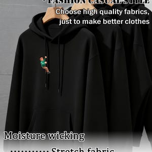 May include: Black hoodie with a drawstring hood and a kangaroo pocket. The hoodie features a small graphic of a person climbing on the front. Text on the image reads "TRENDY PRINTED HOODIE - FASHION CASUAL STYLE" and "Choose high quality fabrics, just to make better clothes."