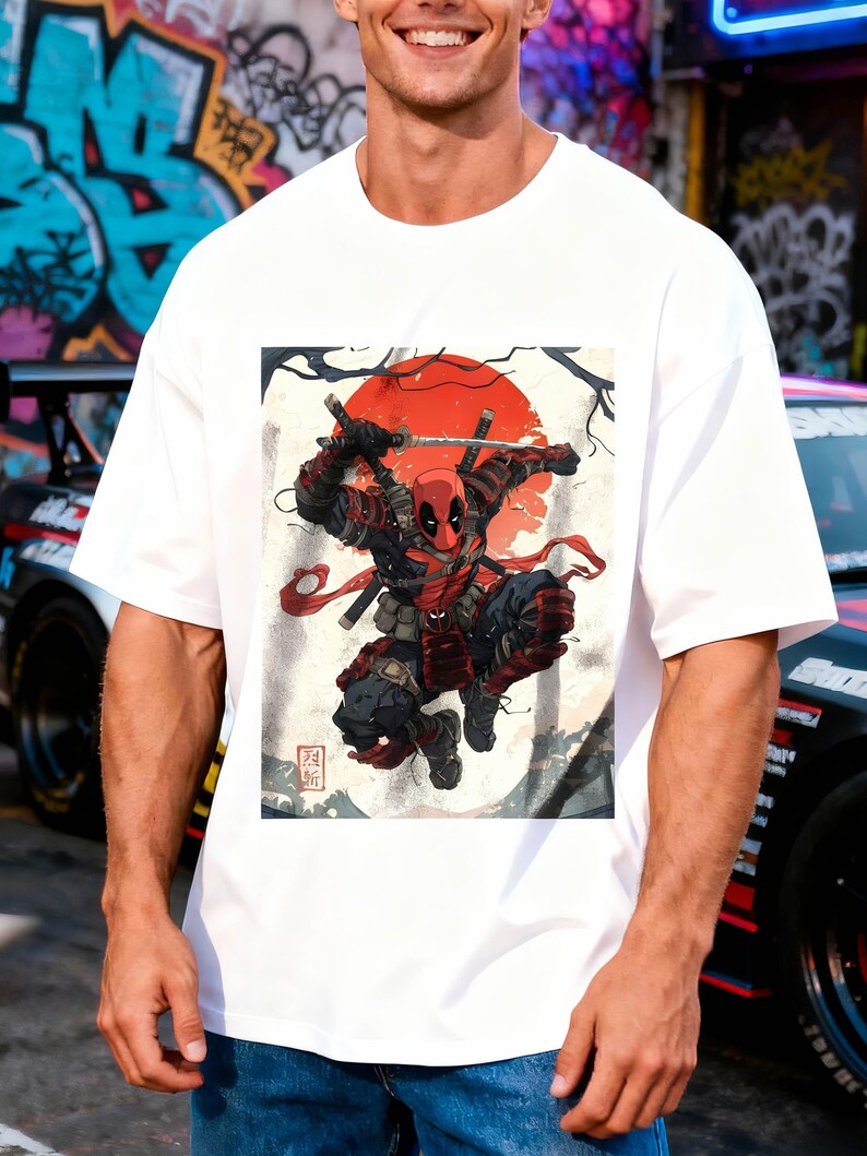 Puede incluir: Camiseta blanca con un gr&aacute;fico de Deadpool empu&ntilde;ando espadas, sobre un sol rojo y un fondo de inspiraci&oacute;n japonesa. El personaje lleva un traje rojo y negro. La camiseta tiene un corte holgado y oversize.