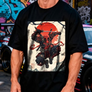 Puede incluir: Camiseta negra con un dise&ntilde;o de Deadpool en pose de samur&aacute;i, con un sol rojo de fondo. El dise&ntilde;o incorpora espadas y elementos de arte japon&eacute;s. Prenda de vestir casual.