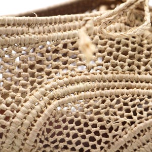 May include: Close-up of a woven basket made from natural fibres. The basket is light brown in colour and has a delicate, intricate pattern.