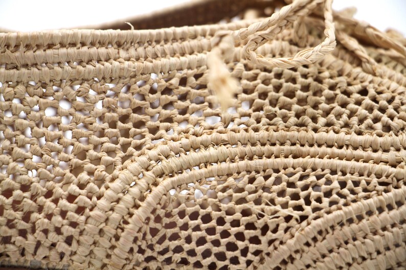 May include: Close-up of a woven basket made from natural fibres. The basket is light brown in colour and has a delicate, intricate pattern.