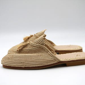 K&ouml;nnte beinhalten: Beigefarbene geflochtene Strohslipper mit Quasten-Detail. Die Slipper haben eine Ledersohle.
