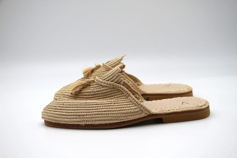K&ouml;nnte beinhalten: Beigefarbene geflochtene Strohslipper mit Quasten-Detail. Die Slipper haben eine Ledersohle.