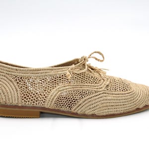 May include: Beige woven crochet flat shoes with a lace-up design.