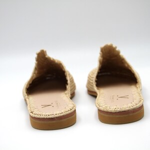 K&ouml;nnte beinhalten: Ein Paar beigefarbene, geflochtene Strohsandalen mit Ledersohle. Die Sandalen haben ein schlichtes Design mit einem geflochtenen Obermaterial und einer geschlossenen Zehenpartie.