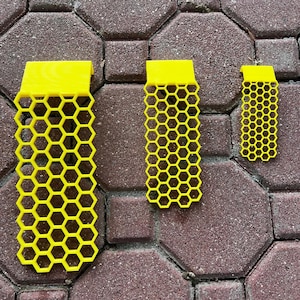 May include: Three bright yellow, rectangular honeycomb-patterned grid panels of varying sizes, each featuring a solid top section and a repeating hexagonal cutout design throughout the main body, arranged vertically in a row from largest to smallest.