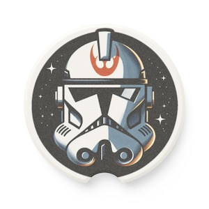 May include: A white and blue Star Wars Stormtrooper helmet with a red Rebel Alliance symbol on the top. The helmet is set against a black background with white stars.