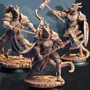 May include: Three detailed figurines of dragon-like warriors in armor, each posed with weapons. The figures are in shades of beige and brown, standing on textured bases. One holds a hammer, another a sword, and the third a shield and axe.