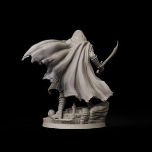 May include: A detailed figurine of a cloaked figure holding a curved sword, standing atop a rocky base with a small castle. The figure is wearing a hooded cloak that drapes dramatically. The statue is a neutral color, set against a black background.