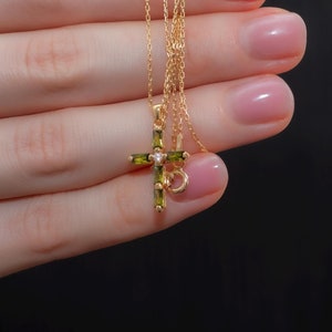 Peut inclure: Un collier en chaîne dorée avec un pendentif en forme de croix en pierre précieuse verte.
