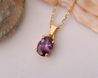 May include: A gold chain necklace with a purple oval-shaped gemstone pendant.