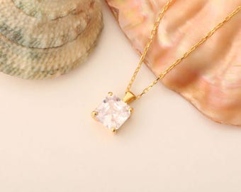 May include: A gold chain necklace with a square-shaped clear cubic zirconia pendant.