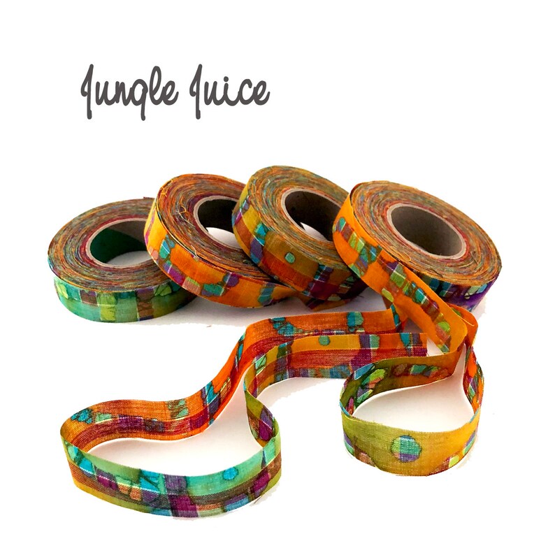 May include: Four spools of colorful fabric ribbon with a geometric pattern in shades of orange, green, purple, and blue. The ribbon is unraveled and lying on a white background. The text "Jungle Juice" is written above the ribbon.