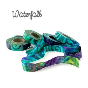 May include: A close-up of a pile of teal, purple, and green fabric ribbon with a paisley pattern. The ribbon is arranged in a loose pile, with some of the ribbon overlapping. The ribbon is called "Waterfall".
