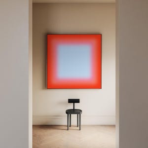 May include: A square wall art piece featuring a gradient transition from a bright red outer border to a soft light blue center. Below the artwork sits a small, black, three-legged stool with a horizontal backrest and a circular seat.