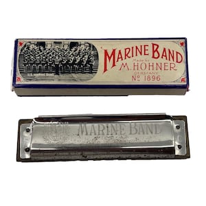 以下が含まれることがあります： 木製のコームが付いた銀色の金属製ハーモニカで、Marine Bandという文字とCという文字が刻印されています。バンドの白黒写真とMarine Band M. Hohnerという文字が印刷された長方形の厚紙製の箱が付属しています。