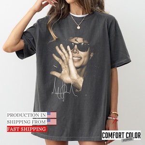 May include: Dark gray Comfort Colors t-shirt featuring a sepia-toned image of a person wearing sunglasses and raising their hand. The shirt includes a printed signature and the text "COMFORT COLOR PEPPER".