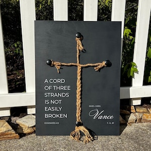 May include: A black chalkboard with a rope cross and the text "A cord of three strands is not easily broken, Ecclesiastes 4:12". Below the cross is the text "David & Carol Vance, 9.16.89".