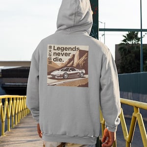 May include: A gray hooded sweatshirt with a graphic print of a white sports car driving through a mountain landscape. The text "Legends never die." is printed on the graphic, along with Japanese characters.