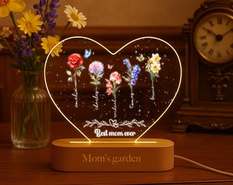 May include: A heart-shaped LED night light with a wooden base. The light features a floral design with the text "Best mom ever" and "Mom's garden".