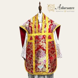 May include: A red and gold liturgical chasuble with floral embroidery and a white lace alb. The chasuble has a gold trim and a gold cross on the front. The alb has a lace trim.