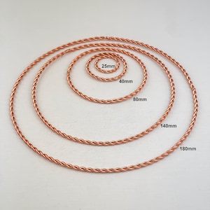 May include: Copper-colored twisted wire rings in various sizes. The smallest ring is 25mm, followed by 40mm, 80mm, 140mm, and the largest is 180mm. The rings are arranged in a spiral pattern, showcasing the different sizes.