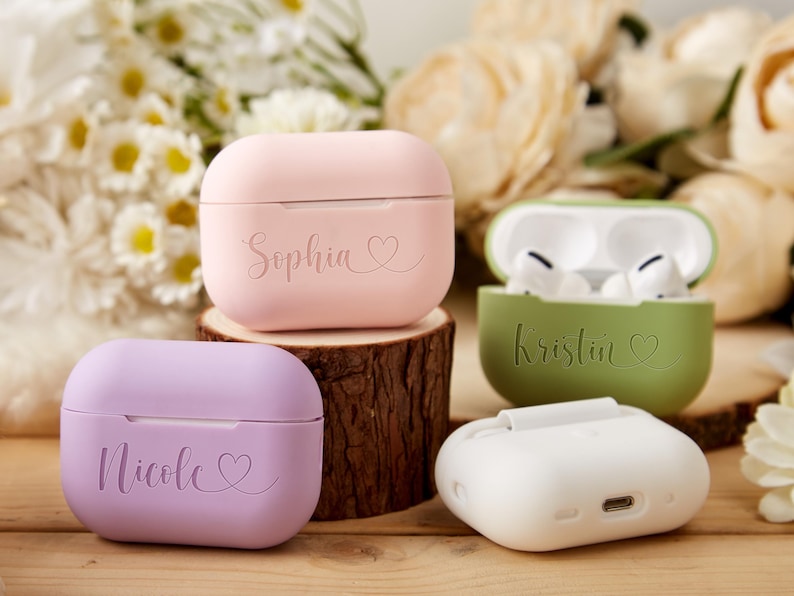 May include: Four personalized AirPod cases in pink, purple, green, and white with the names Sophia, Kristin, Nicole, and a heart symbol.