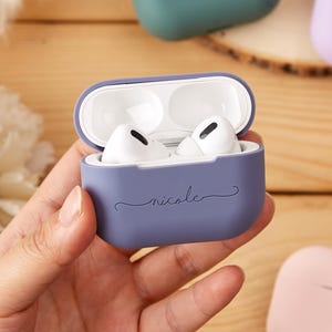 May include: A purple silicone case for AirPods with the name "nicole" written on it in a cursive font.